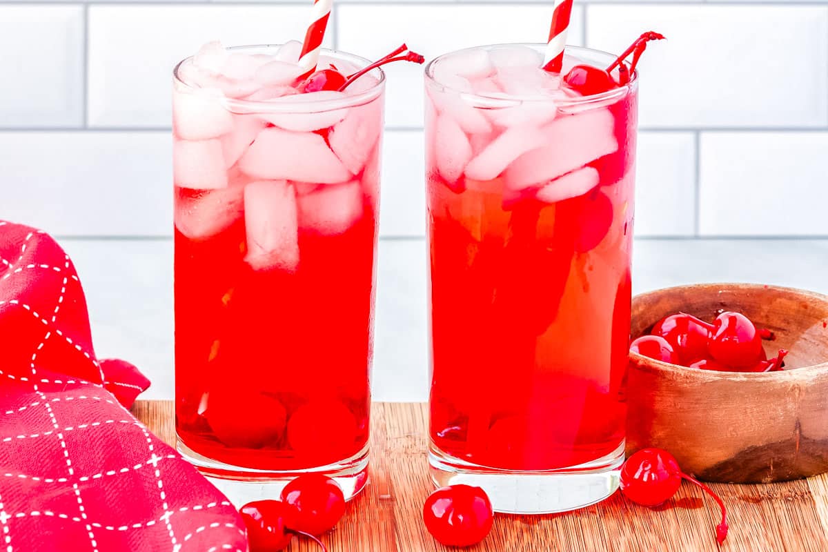Two glasses of a red mocktail on a serving board.