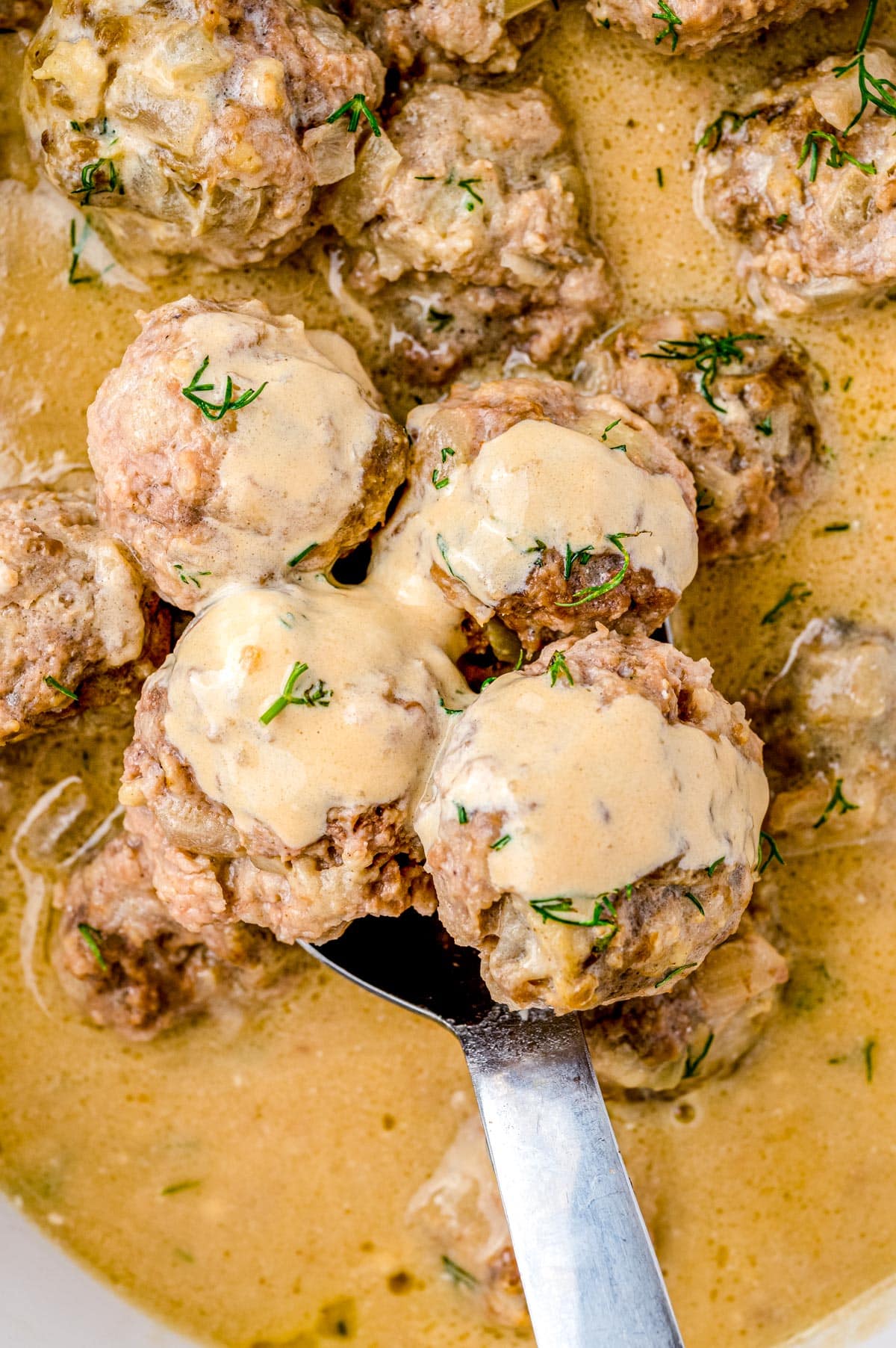 A close up picture of the Slow Cooker Swedish Meatballs being scooped up with a spoon.