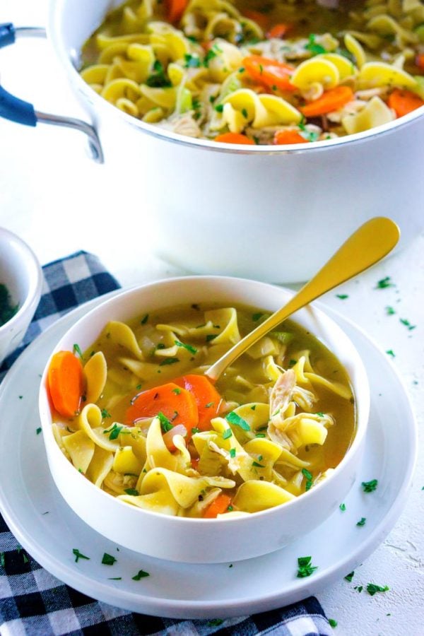 Rotisserie Chicken Noodle Soup recipe in a white bowl with a golden spoon.