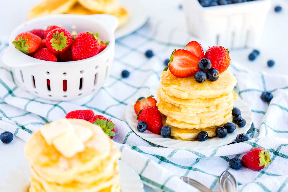 A stack of buttermilk pancakes with fruit on top