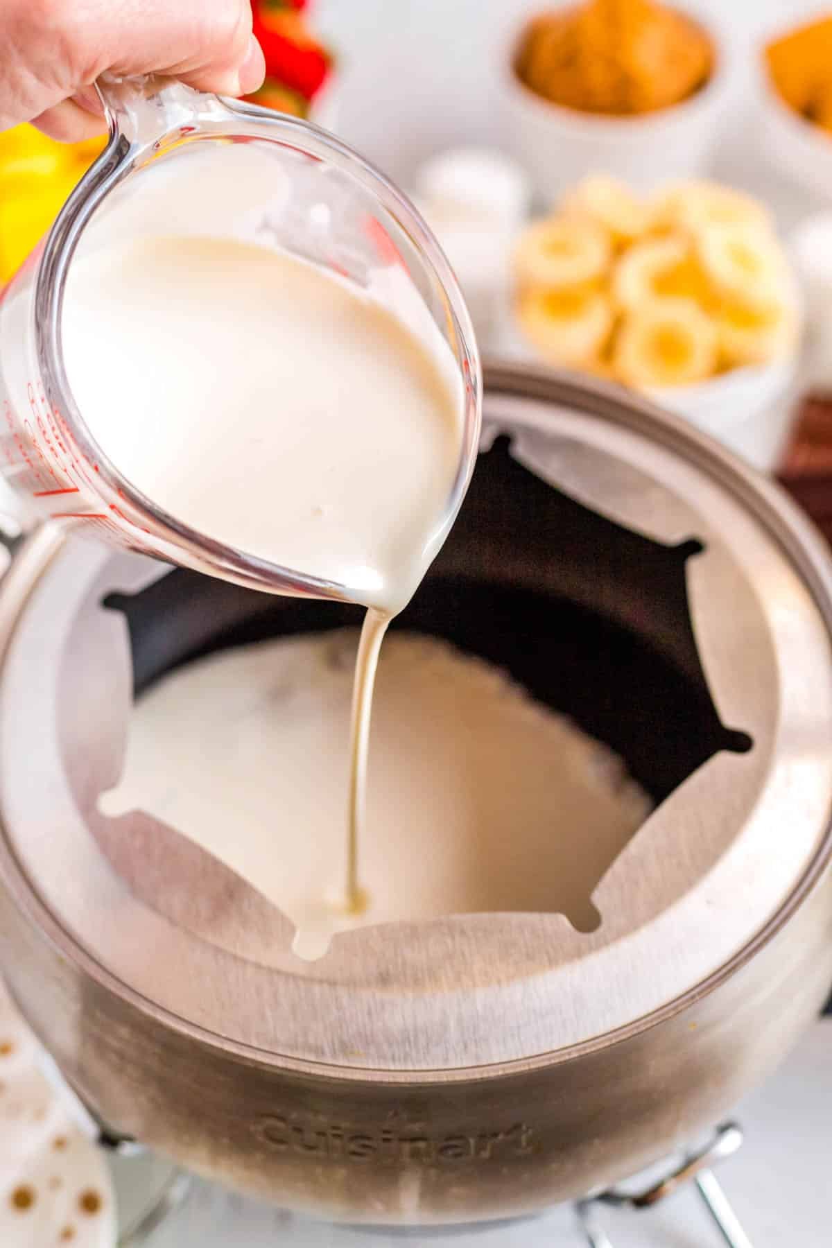 Cream being poured into an electric fondue pot. 