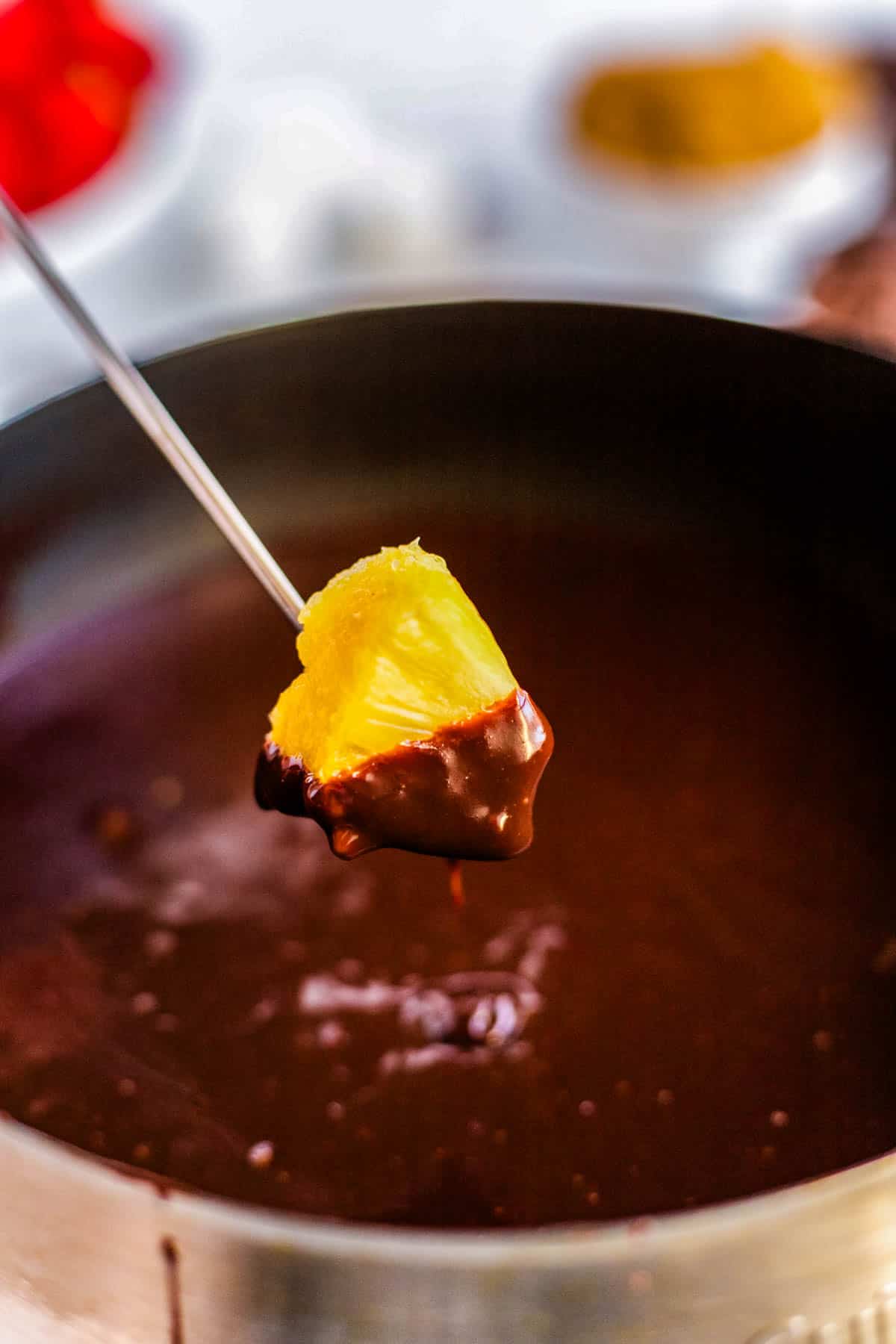 A piece of pineapple that was just dipped into milk chocolate fondue.