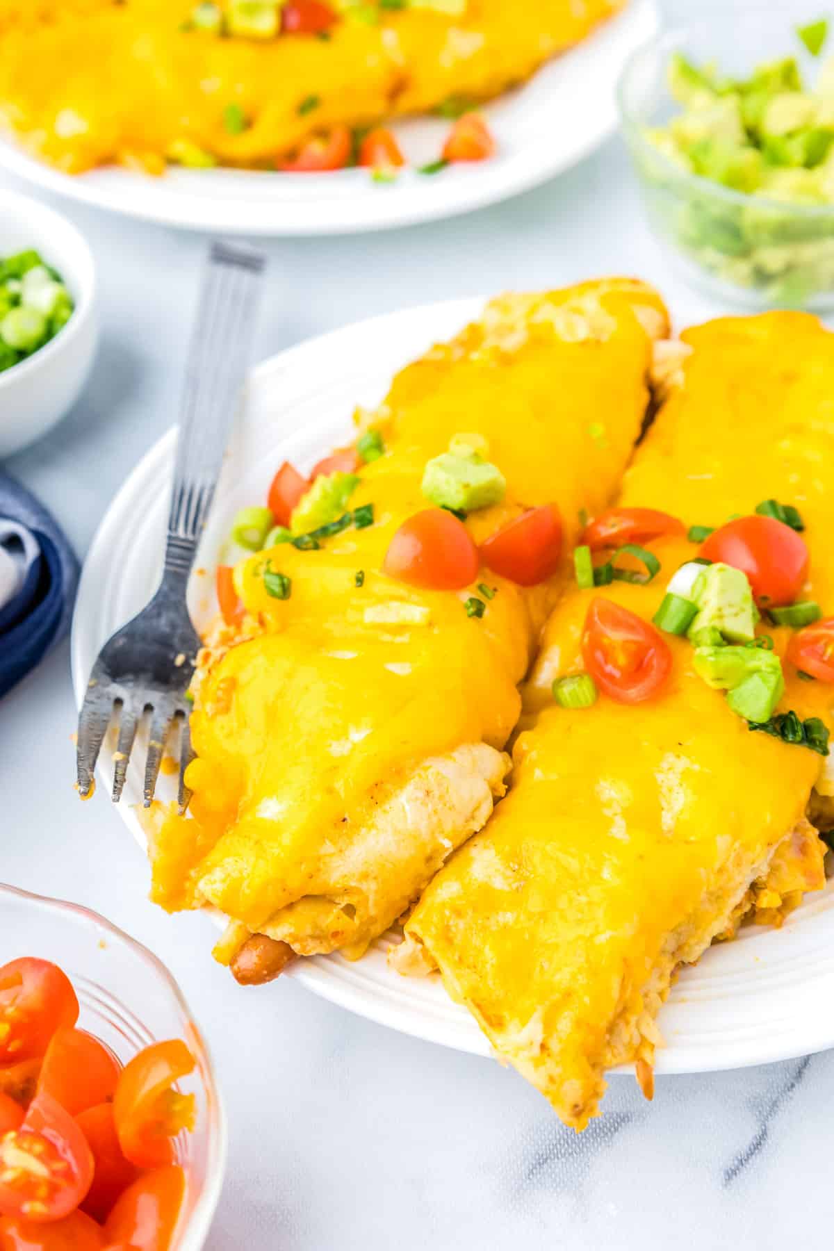 A close up picture of two Breakfast Enchiladas on a white plate.