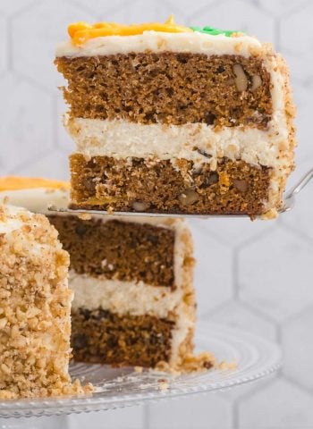 A slice of Cheesecake Factory Carrot Cake being taken from the whole cake.