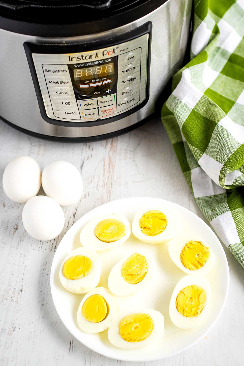 Hard-boiled eggs on a plate with an Instant Pot in the background