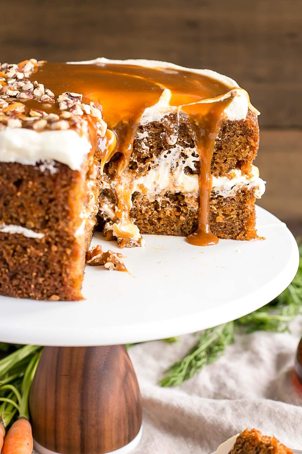 Layered round carrot cake with caramel dripping off of it.