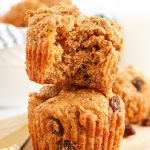 Two Bran Muffins stacked on top of each other. The top one has a bite taken out of it.
