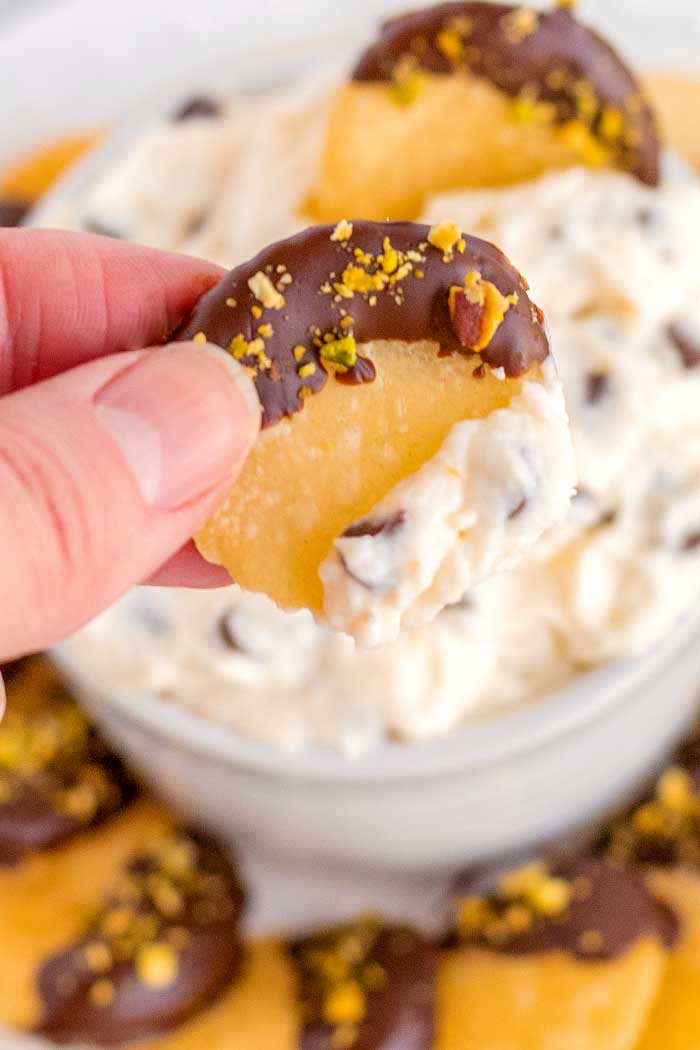 A chocolate-covered cannoli chip dipped in Cannoli Dip