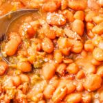 A spoon scooping up some of the finished crockpot pinto beans.