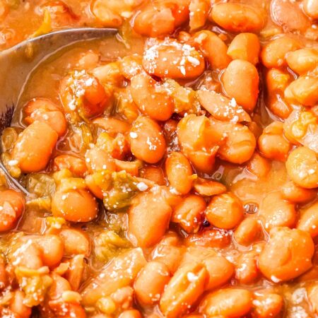 A spoon scooping up some of the finished crockpot pinto beans.