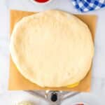 The rolled-out homemade pizza dough on a pizza peel.