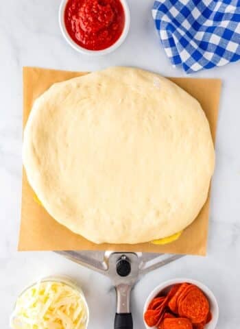 The rolled-out homemade pizza dough on a pizza peel.
