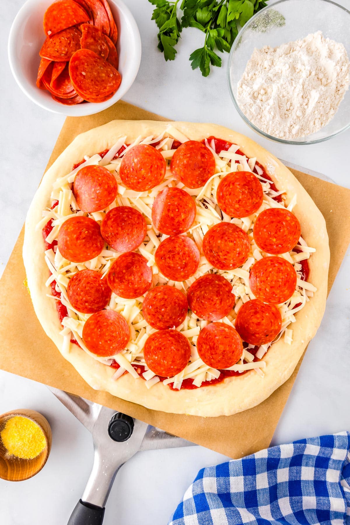 Rolled out homemade pizza dough topped with sauce, cheese, and pepperoni.