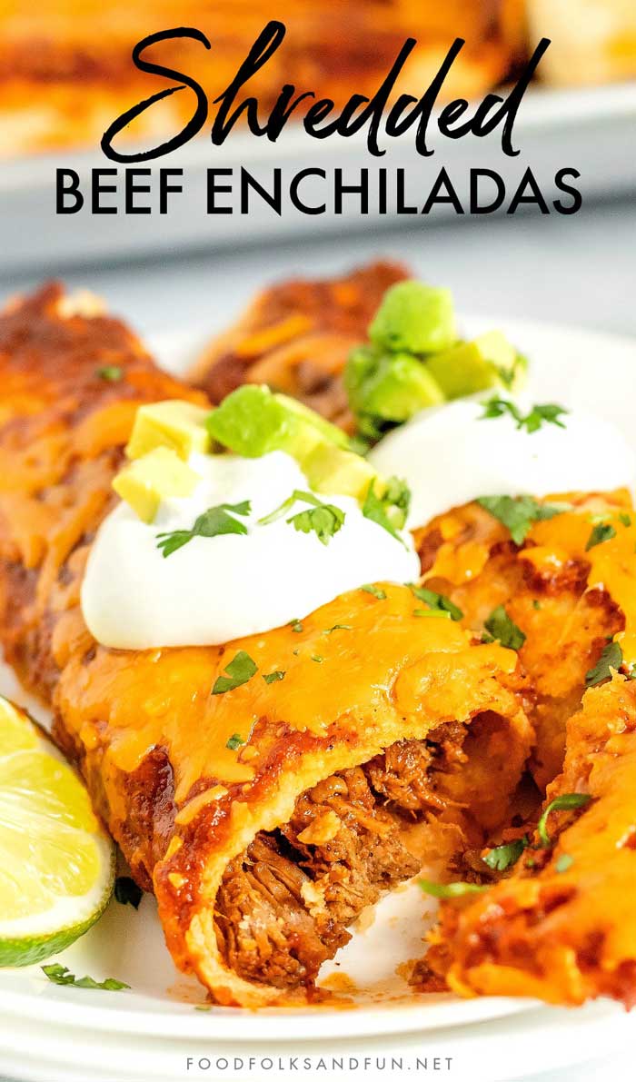 Two rolled shredded beef enchiladas topped with sour cream, avocado, and cilantro.