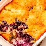 The finished blueberry lemon cobbler in a baking pan with scoops taken out of it so you can see what the inside looks like.