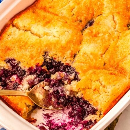 The finished blueberry lemon cobbler in a baking pan with scoops taken out of it so you can see what the inside looks like.