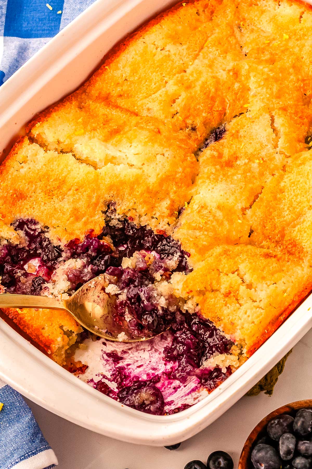 The finished blueberry lemon cobbler in a baking pan with scoops taken out of it so you can see what the inside looks like.