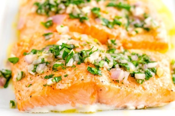 Close up picture of baked salmon with lemon vinaigrette on top.