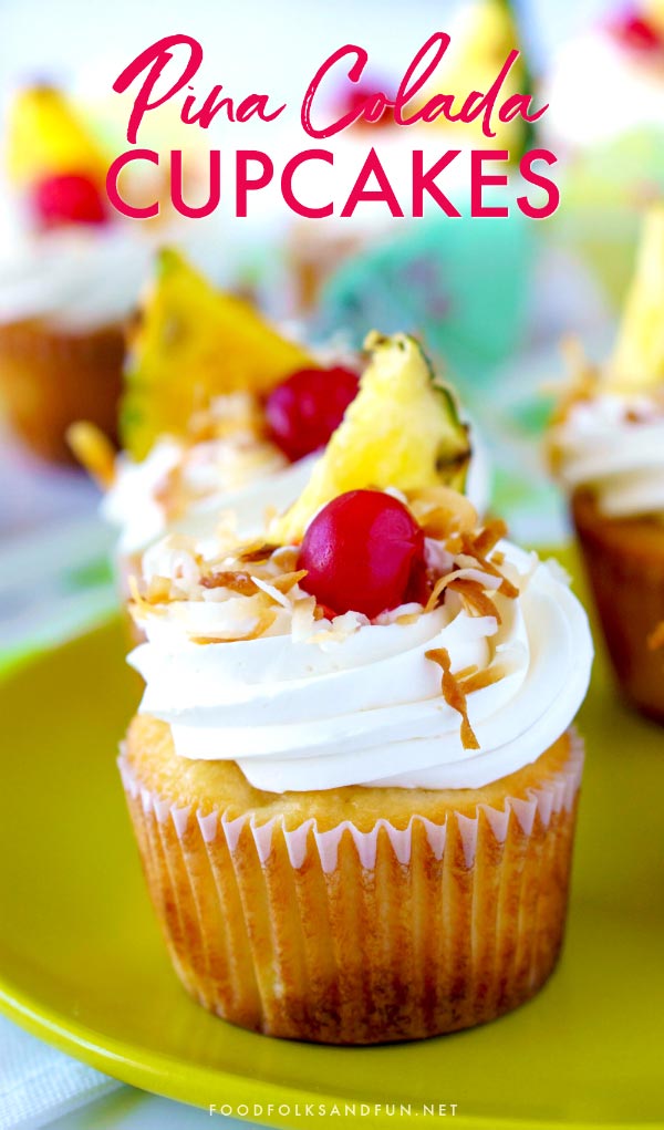 Pina Colada Cupcakes garnished with toasted coconut, pineapple, cherries, and a paper umbrella.
