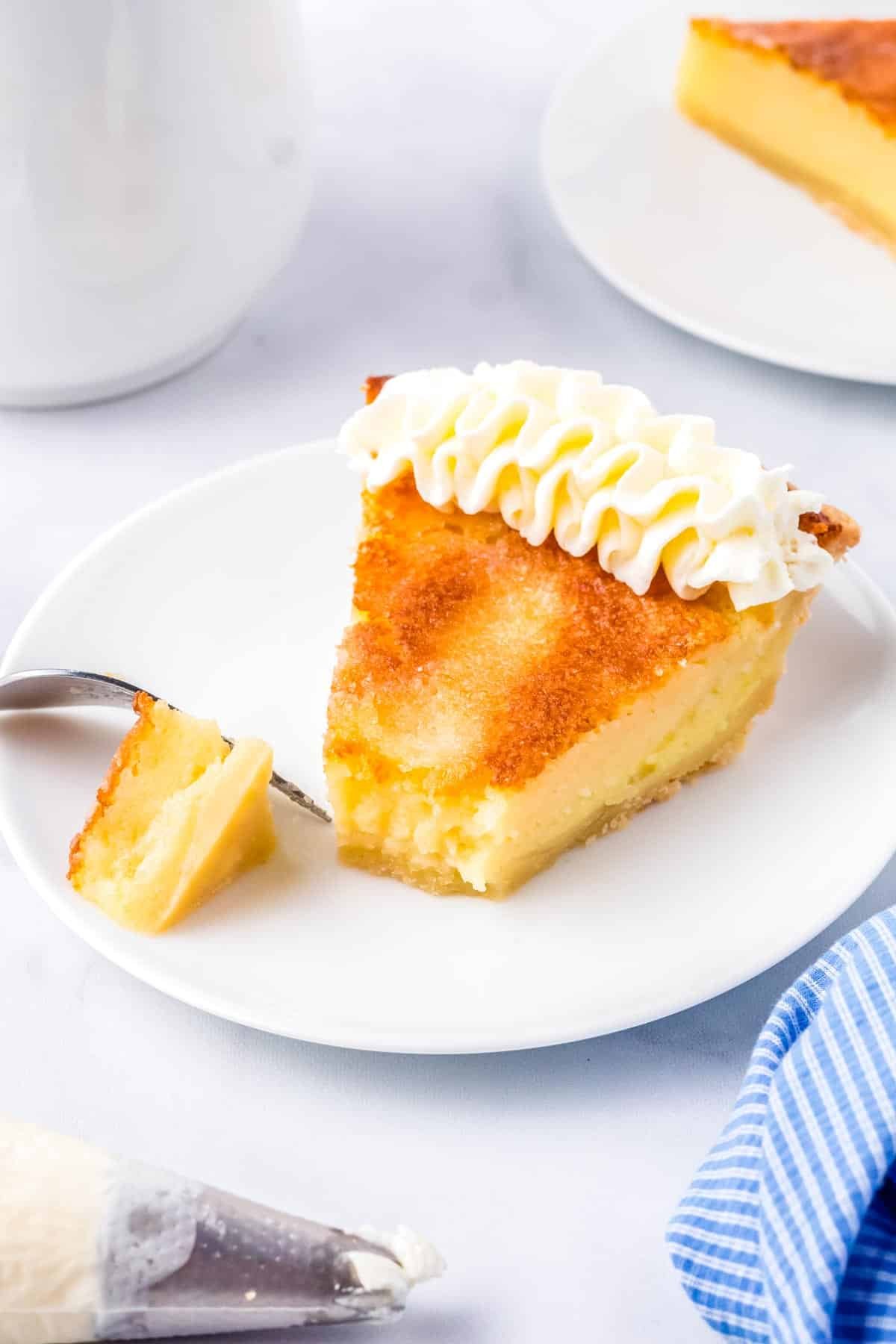 A slice of Buttermilk Pie on a white plate garnished with whipped cream.