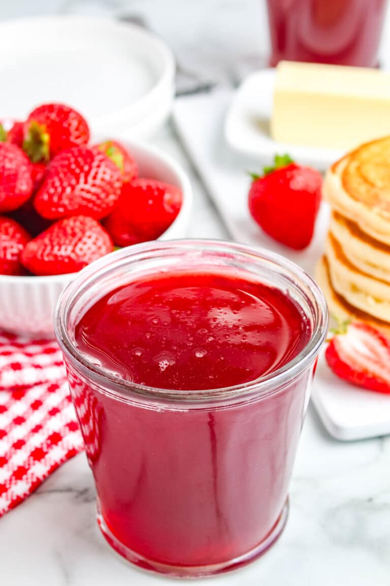 A jar filled with strawberry syrup.