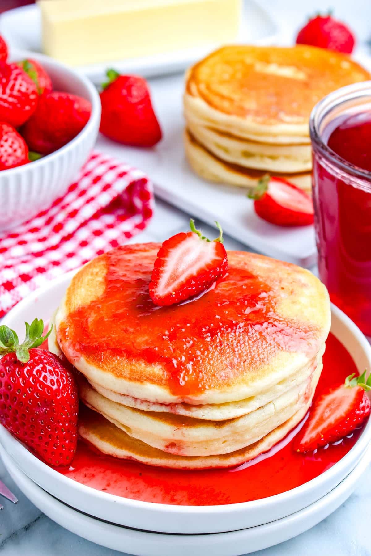 The finished Strawberry Syrup recipe poured over a stack of pancakes.