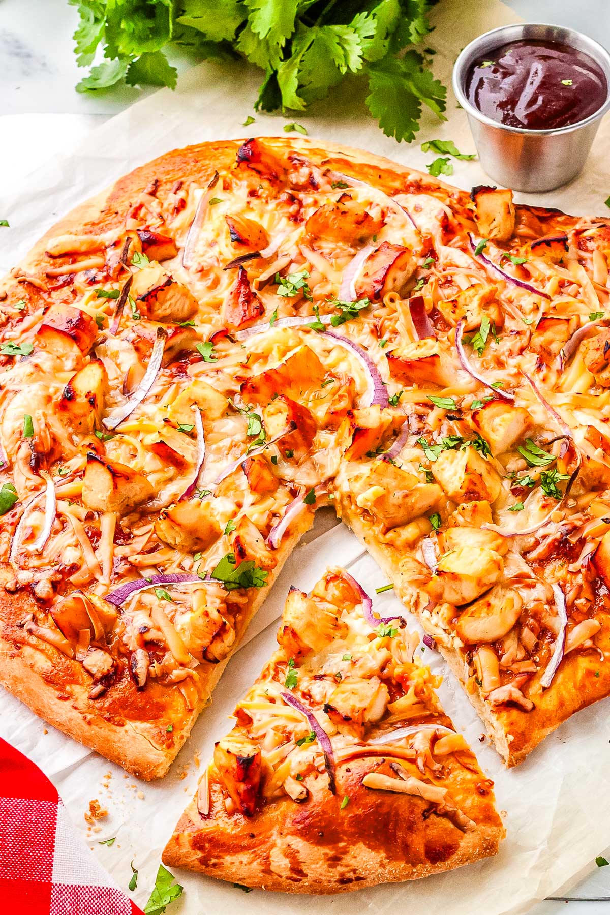 BBQ Chicken Pizza California Pizza Kitchen copycat on a cutting board with a slice cut from it.