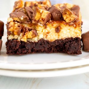A close up picture of the finished Snickers brownies on a white plate.