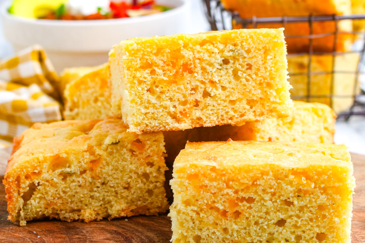 Close up of cheesy green chile cornbread showing golden edges and fluffy interior with cheddar cheese.