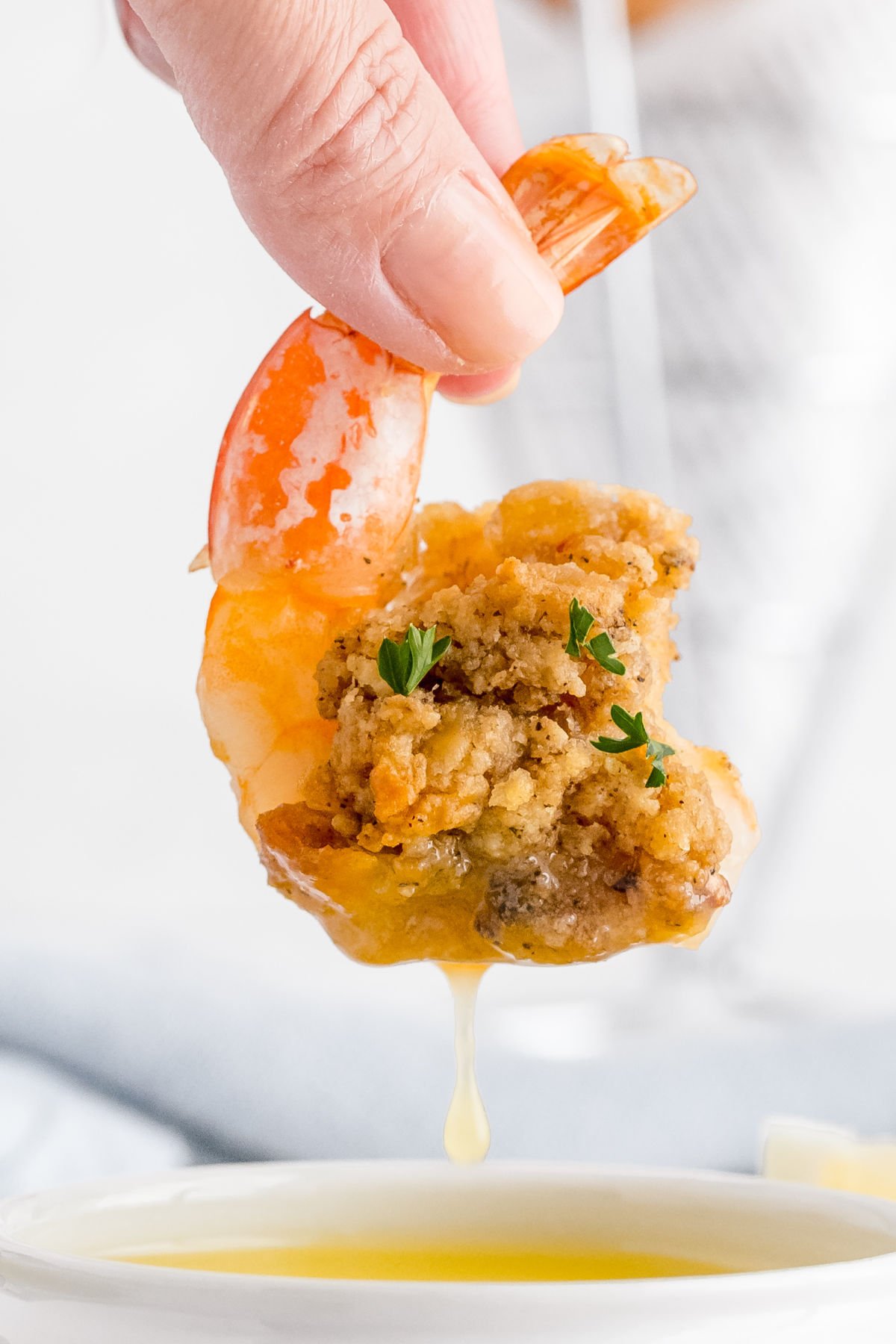 A baked stuffed shrimp being dipped into melted butter.