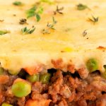 A close up picture of a slice of classic shepherd's pie recipe on a white plate.