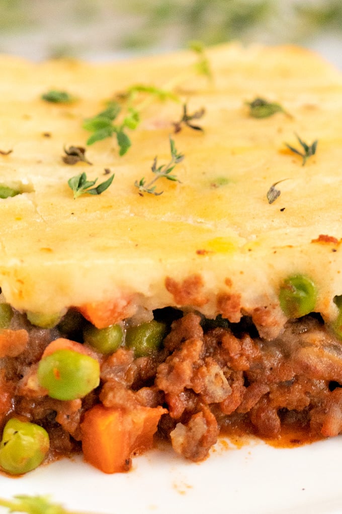 A close up picture of a slice of classic shepherd's pie recipe on a white plate.