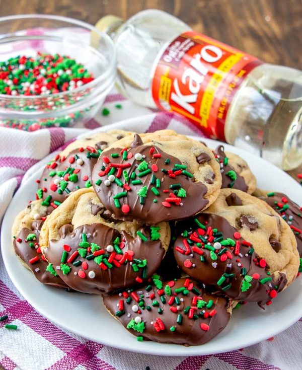 Chocolate chip cookies that are half dipped in chocolate and covered with Christmas sprinkles.