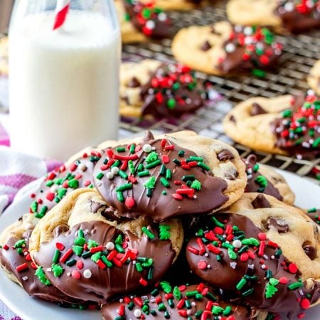 Dipped Christmas Chocolate Chip cookies on a plate with Christmas sprinkles.
