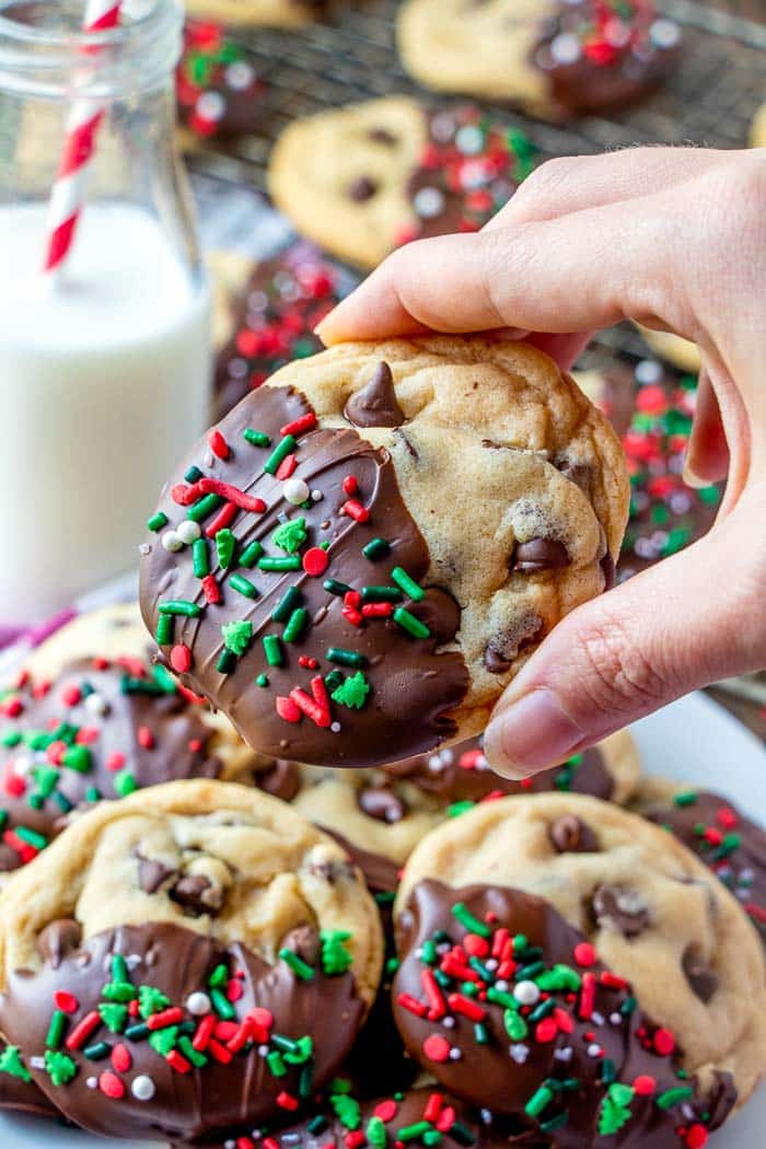 A hand picking up a dipped chocolate chip cookies.