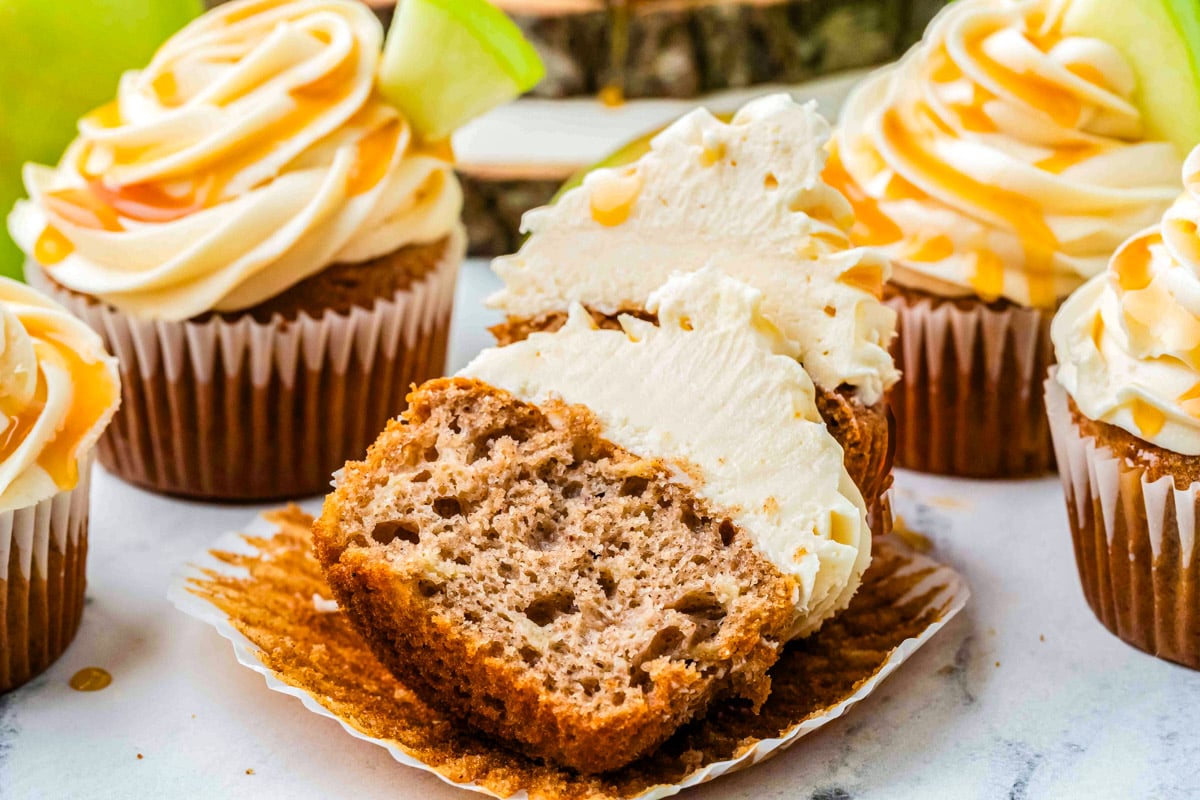 Caramel apple cupcake sliced open to show moist spiced apple crumb, topped with creamy caramel frosting.
