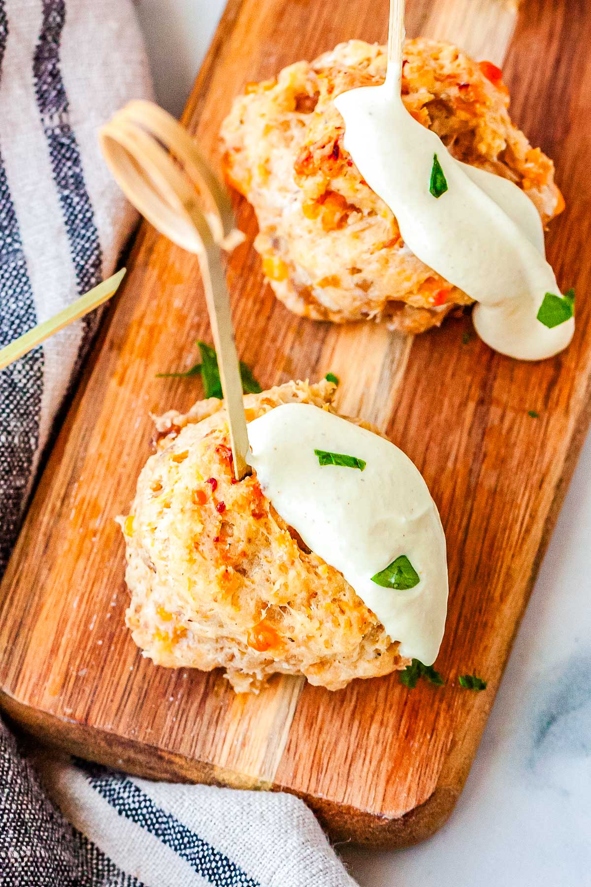 Two sausage balls with toothpicks in them on a wooden serving board.