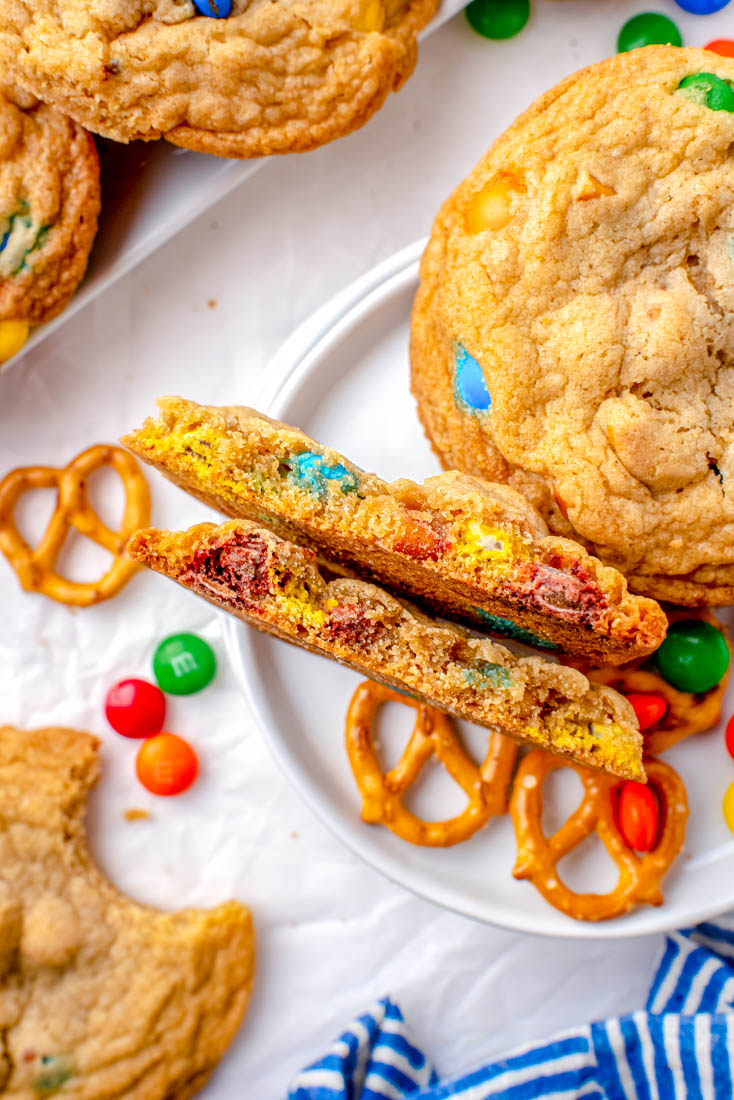 Pretzel Cookies with M&Ms and one of them is broken in half to show what the interior looks like.