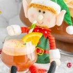 A cute stuffed elf sipping on a glass of non-alcoholic Christmas Punch.