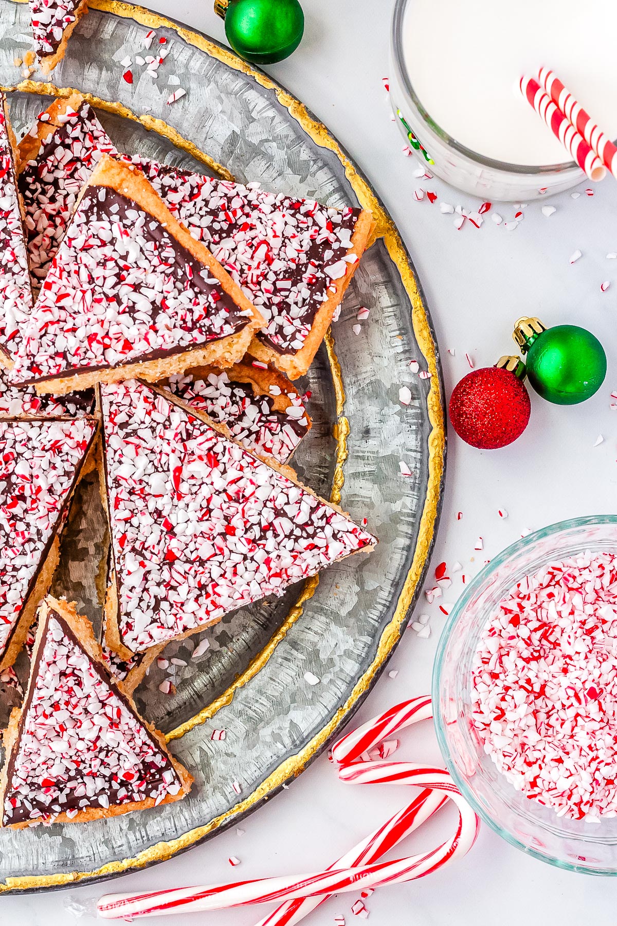 Peppermint Bark Cookies arranged on a platter with candy canes and a glass of milk nearby.