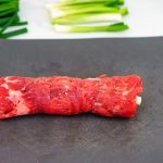 Place the scallions on the bottom of the meat square and roll into a cylinder.