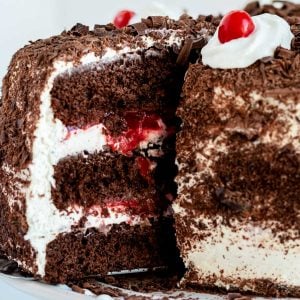 A close up picture of a slice of black forest cake being taken from the larger cake.