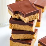 A stack of No-Bake Chocolate Peanut Butter Bars with a bite taken out of the top one.