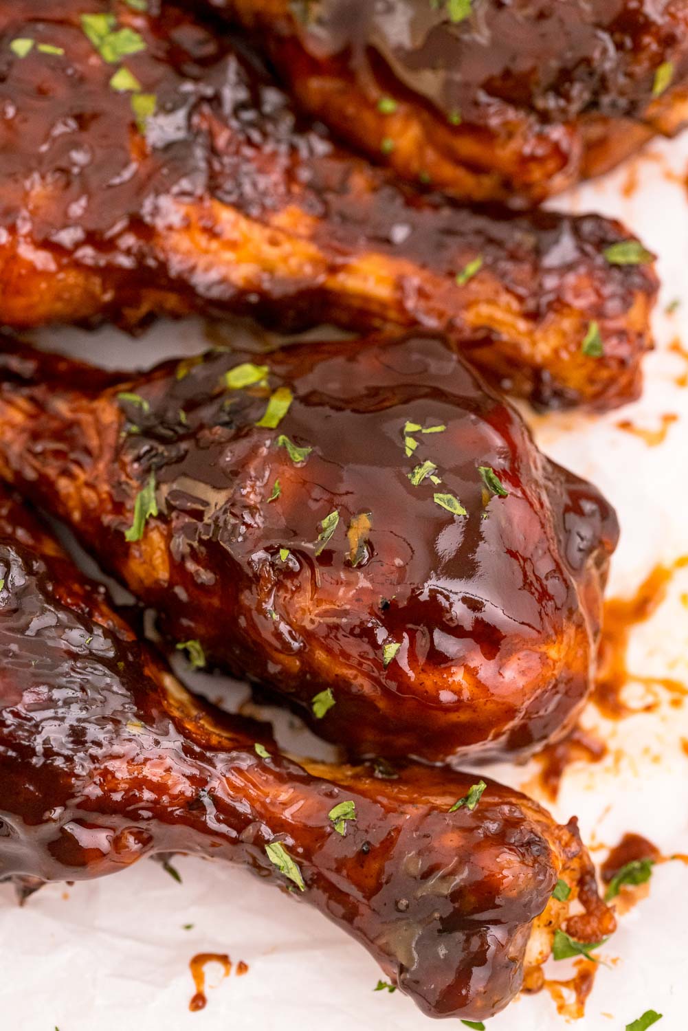 A close up picture of Baked BBQ Chicken Drumsticks on parchment paper.