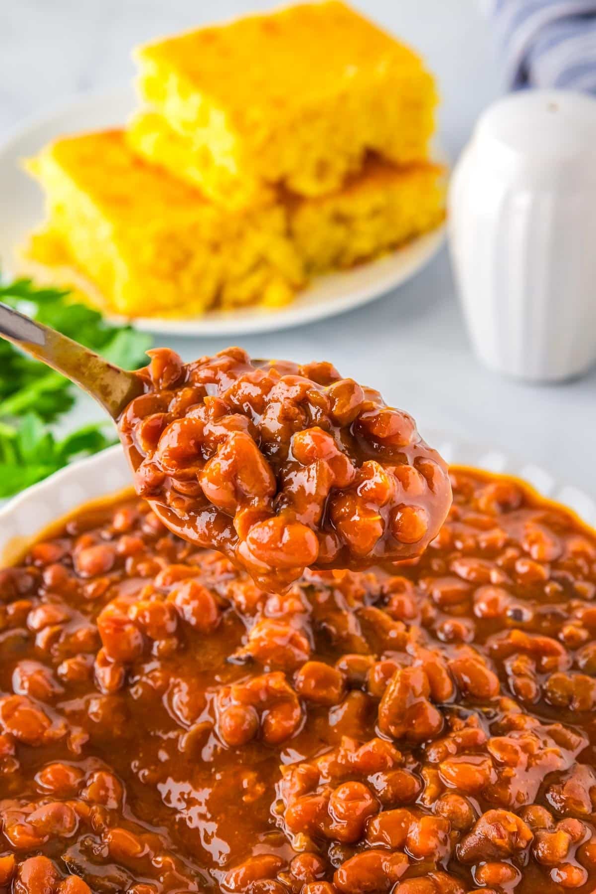 A serving spoon picking up some of the crock pot baked beans.