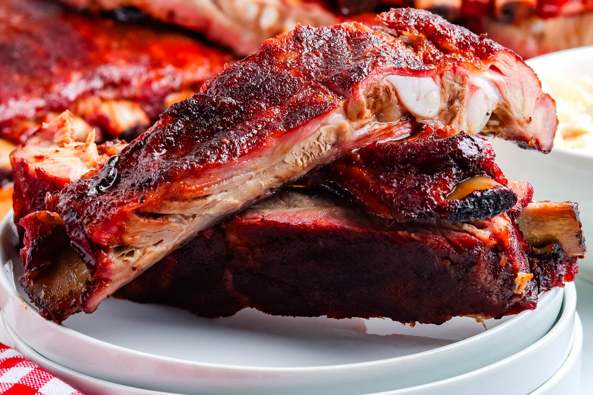 Three smoked ribs on a white plate.
