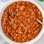 An overhead picture of the finished slow cooker baked beans in a white serving dish.