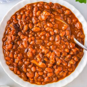 An overhead picture of the finished slow cooker baked beans in a white serving dish.