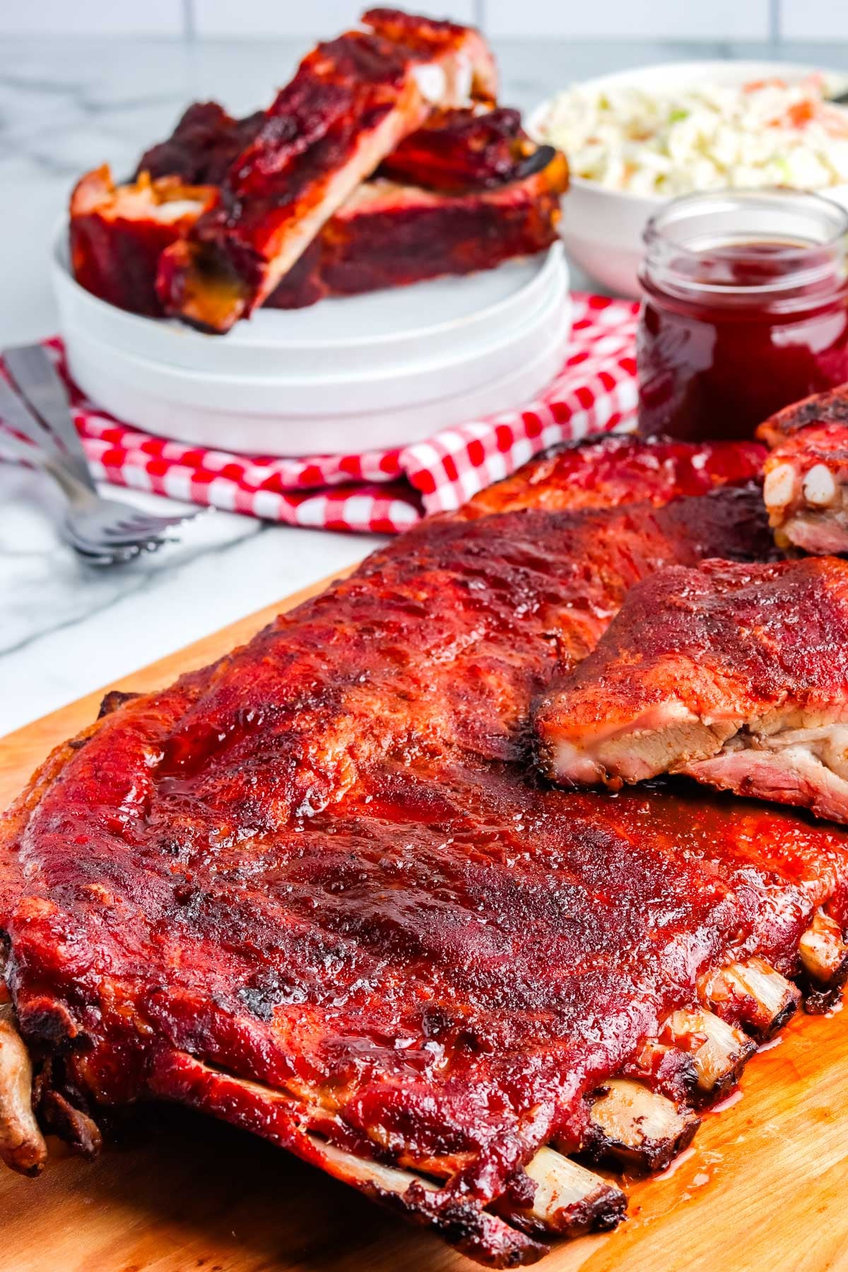 A rack of smoked pork spare ribs on a wooden cutting board.