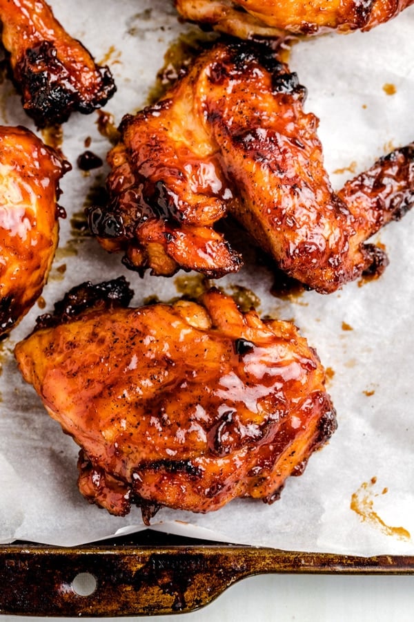 Close up picture of a piece of grilled BBQ chicken on a piece of parchment paper.